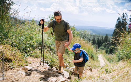 Father with small son hiking outdoors in summer nature, walking. photo