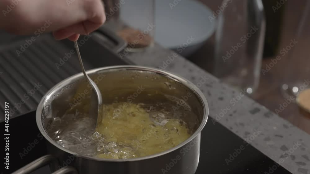 Slow motion man hand stir fettuccine in boiling water in saucepan Slow motion man hand stir fettuccine in boiling water in saucepan