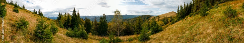 Beautiful autumn panorama of yellow and red trees against the background of big mountains