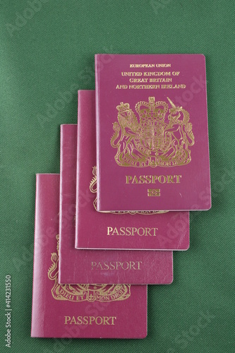 Four British passports isolated on a green background, family holiday concept
