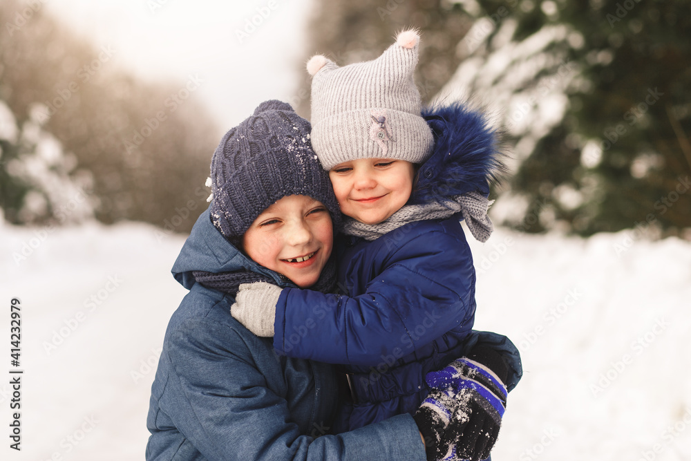 Happy children cuddle in winter in the woods. Brother and sister together Happy children cuddle in winter in the woods. Brother and sister together