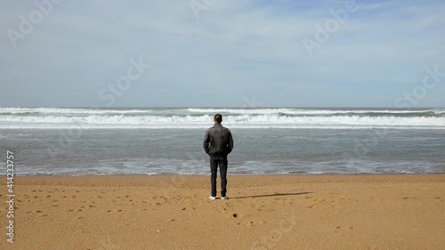 Cinemagraph of man at beach contemplating the sea, only part of the ocean water is in motion