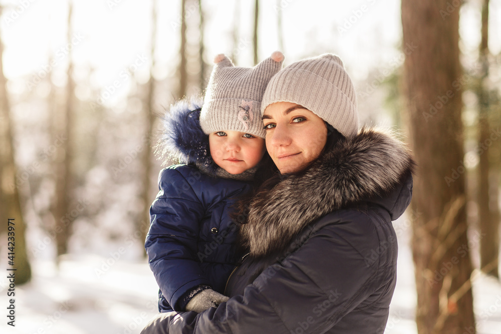 Young mother holds little baby daughter in her arms in winter in the park Young mother holds little baby daughter in her arms in winter in the park