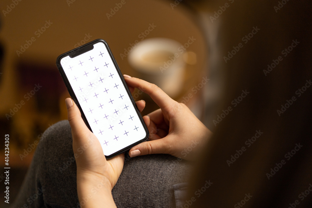 Obraz premium Young women holding her phone in in hand, reading news, browsing internet or digital application, watching video, with white coffee on the table