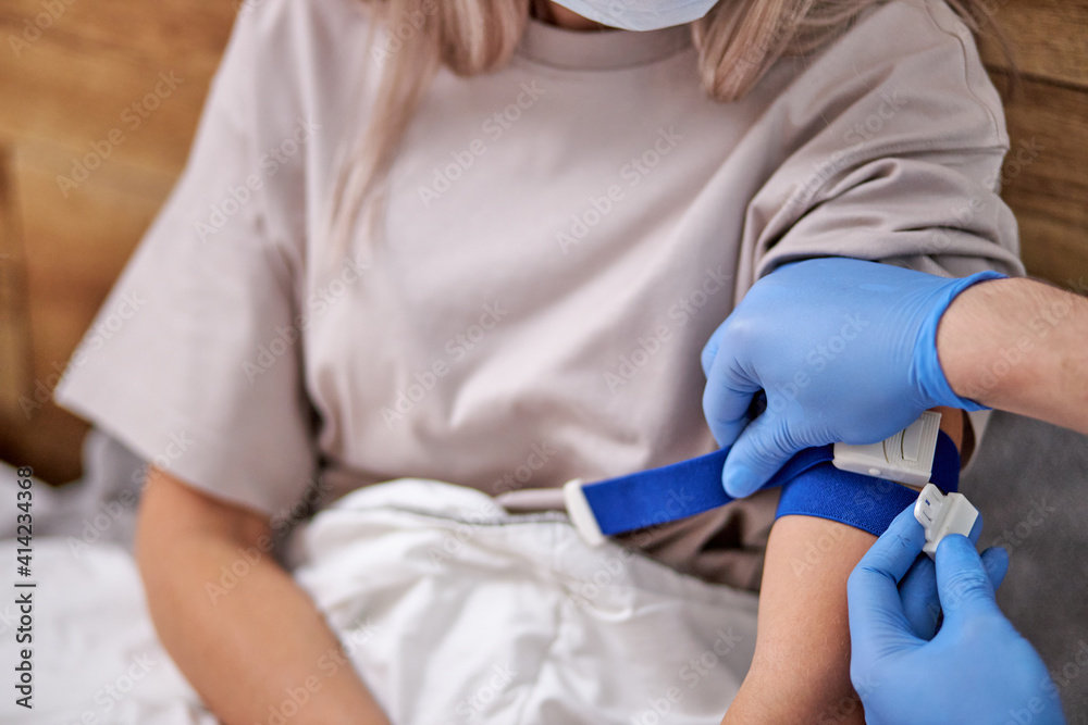 cropped doctor in medical gloves give injection to patient's arm at home doing quarantine. doctor giving a vaccination shot to a young woman patient at home. cropped doctor in medical gloves give injection to patient's arm at home doing quarantine. doctor giving a vaccination shot to a young woman patient at home.