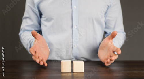 Wooden blocks cubes on the table. Man holding businessman in his hands. Growth and construction concept.