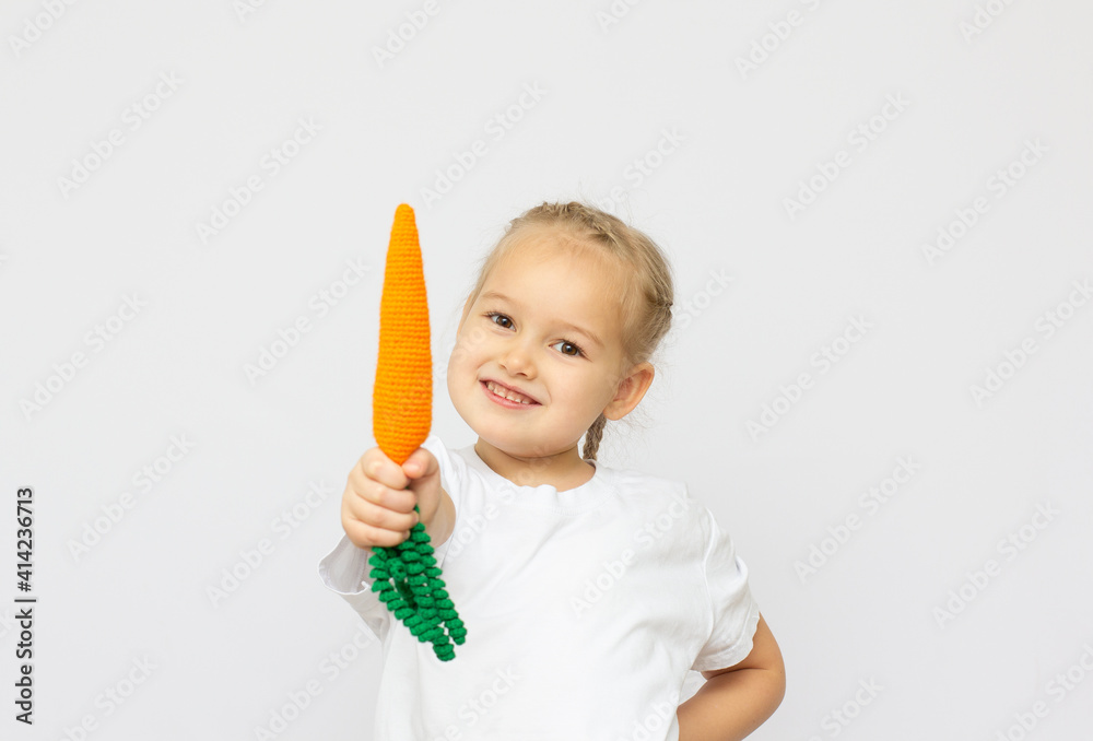 Happy little girl holding a knitt carrots. Concept of healthy food. Happy little girl holding a knitt carrots. Concept of healthy food.