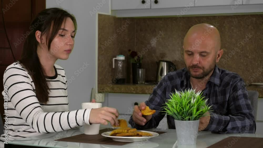 Relaxed young married couple sitting in the kitchen drinking coffee or hot tea while enjoying spending the weekend together. 4k footage Relaxed young married couple sitting in the kitchen drinking coffee or hot tea while enjoying spending the weekend together. 4k footage
