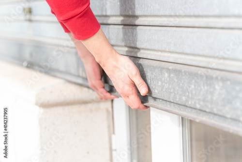 Man's hand closing metal roller shutter door