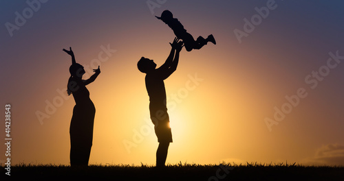 Mother and father playing with child lifting him up in the air. 