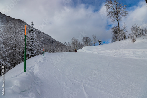 Unknown snowborder on ski slope with mountain background in Rosa Khutor ski resort. Sochi, Russia photo