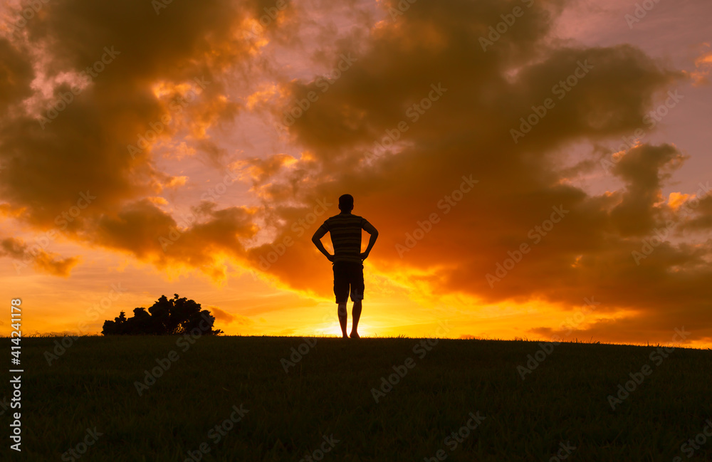 Young man walking into a beautiful sunrise. Happy state of mind concept 