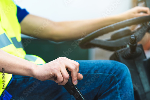 Selective focus shot of man's hand on the steering wheel of a forklift truck in a factory