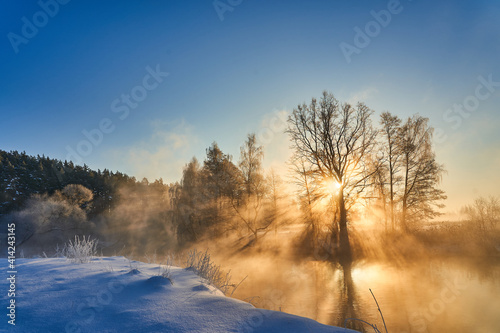 Winter panorama with trees reflected in the lake. Calm winter scene with sunbeams and warm sunlight. Natural winter or christmas background
