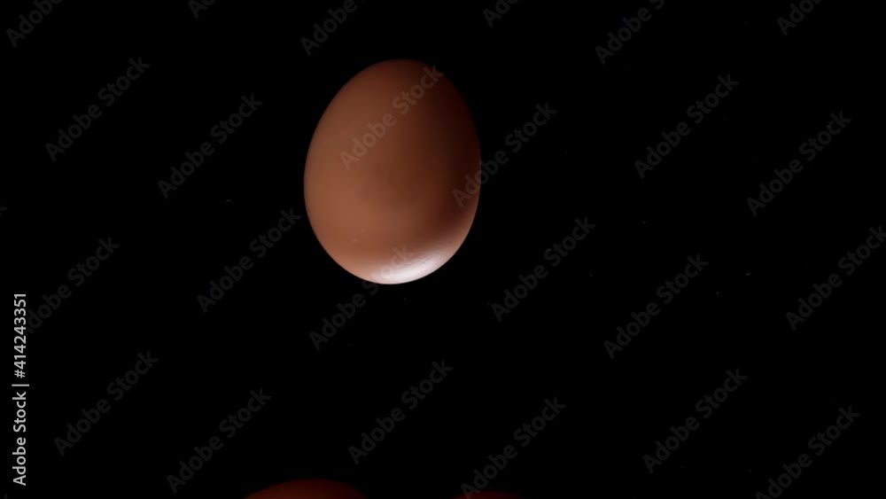 Egg is spinning on a black background. Slow motion of an egg in a shell spinning on glass. Close shot of a spinning egg.
