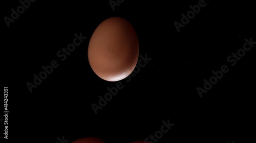 Egg is spinning on a black background. Slow motion of an egg in a shell spinning on glass. Close shot of a spinning egg.