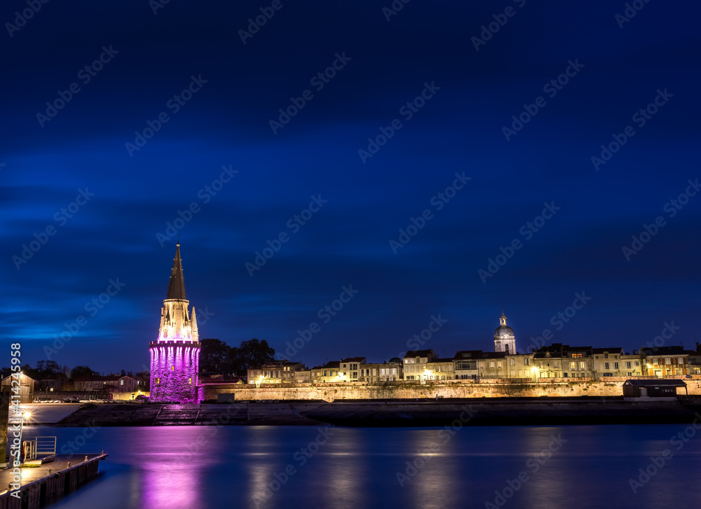 Panoramic view of the old harbor of La Rochelle with its famous towers. night shot with pink lights for pink october. Pink October is breast cancer awareness month
