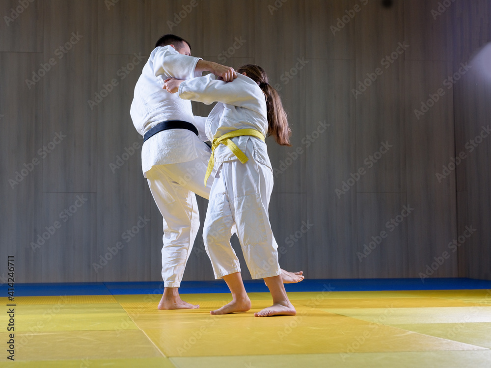 Black belt judoka demonstrating o soto gari technique on young female student Black belt judoka demonstrating o soto gari technique on young female student