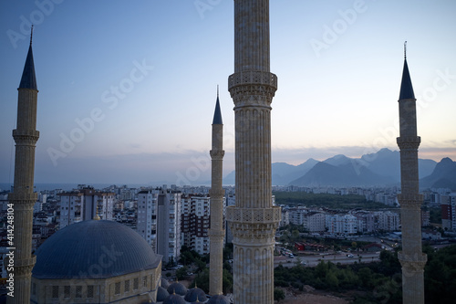 Mosque of the four minarets. High-rise buildings of a modern city with mountains in the background. Picturesque urban landscape in the evening. Antalya, Turkey. photo