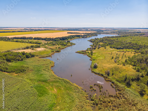 Top view of river, surrounded by trees and meadows on its banks © Ryzhkov Oleksandr