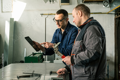 A tinsmith and his fellow colleague engineer in the workshop photo