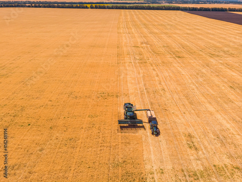 Aerial view of combine harvester agricultural machinery harvesting wheat crops in field