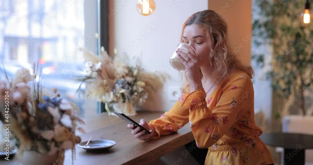 Pretty woman using smart phone sitting in a cafe writing message