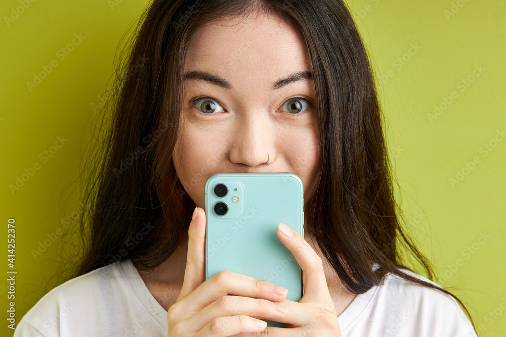 amazed woman hiding reading sms message isolated on green pastel background, stand in shock after reading something, wearing casual white t-shirt amazed woman hiding reading sms message isolated on green pastel background, stand in shock after reading something, wearing casual white t-shirt