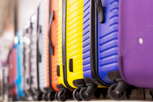 A row of colorful suitcases with wheels in the store.