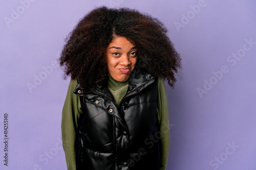 Young african american curly woman isolated on purple background shrugs shoulders and open eyes confused.
