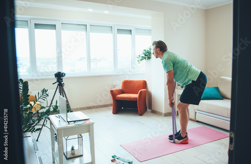Caucasian man is doing fitness exercises on camera at home wearing sportswear