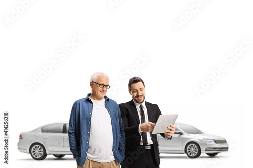 Car salesman and a mature customer looking at a tablet in a car showroom