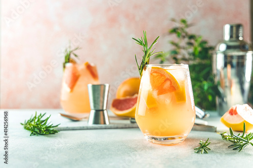 Tequila cocktail or cold lemonade with grapefruit juice, tinted with the aroma of a fresh sprig of rosemary
