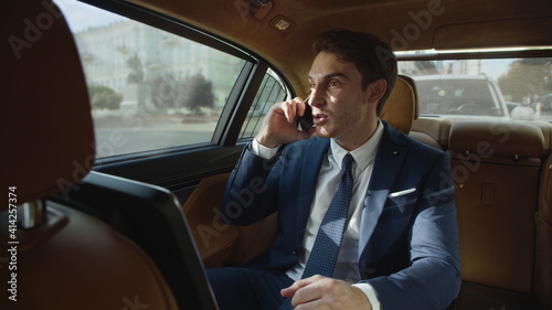 Excited businessman hearing good news on mobile phone in business car. © stockbusters