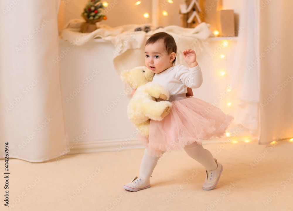 portrait of a baby girl in home interior decorated with lights and holiday gifts portrait of a baby girl in home interior decorated with lights and holiday gifts