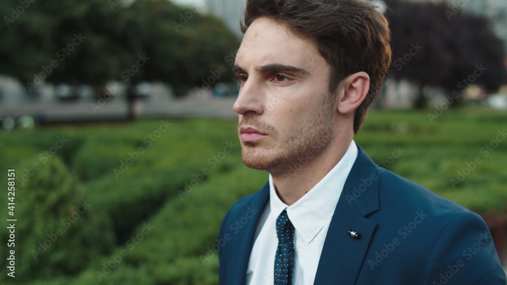 Serious business man walking past public garden. Calm man having citywalk. Serious business man walking past public garden. Calm man having citywalk.