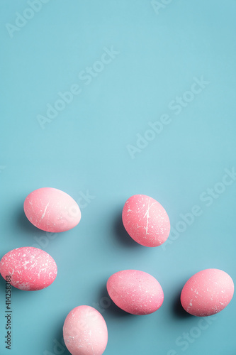Easter flat lay composition with pink eggs on turquoise background. Top view, vertical, minimal style.
