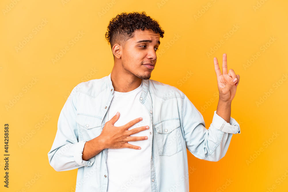 Young african american curly man isolated on purple taking an oath, putting hand on chest. Young african american curly man isolated on purple taking an oath, putting hand on chest.
