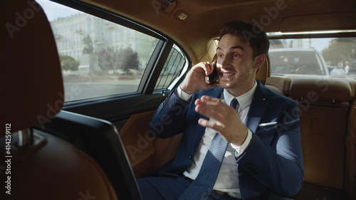 Smiling businessman talking on mobile phone in interior of business car. © stockbusters