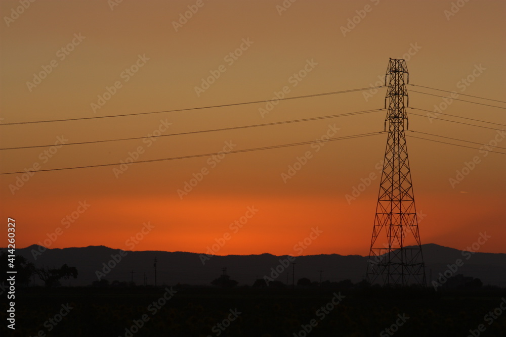 Power plant and electric line across the sky at sunset