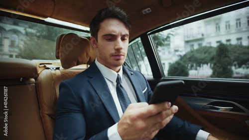 Upset male professional reading bad news on smartphone in salon of business car. © stockbusters