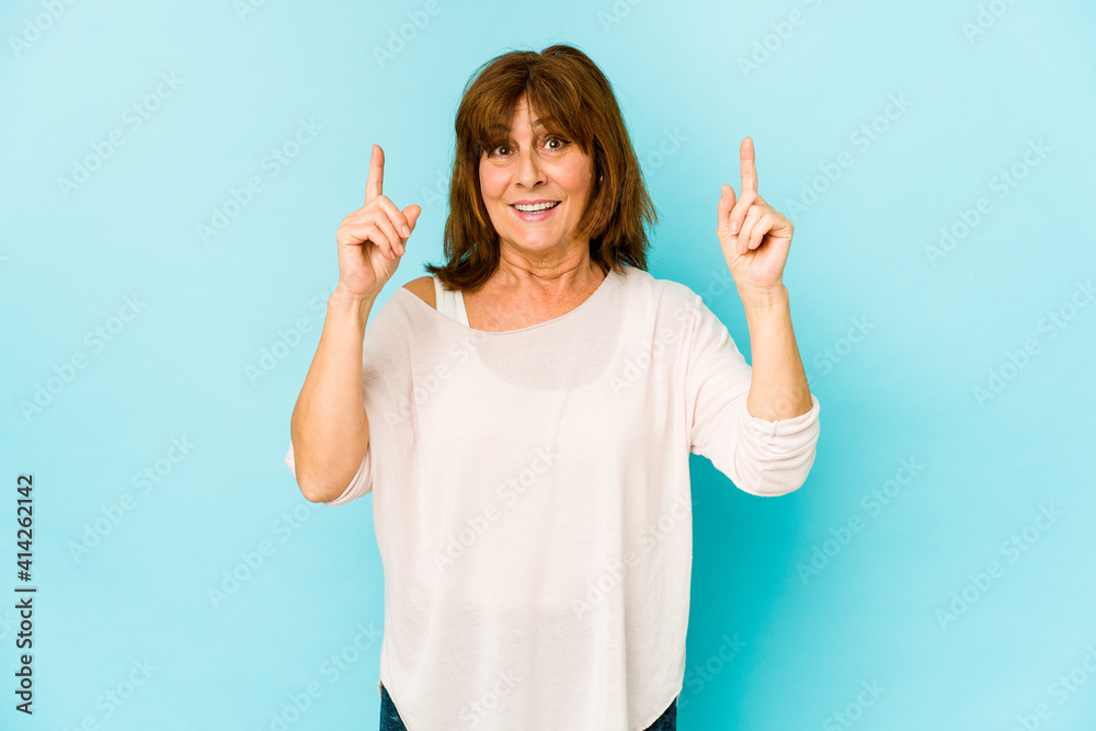 Senior caucasian woman isolated indicates with both fore fingers up showing a blank space. Senior caucasian woman isolated indicates with both fore fingers up showing a blank space.