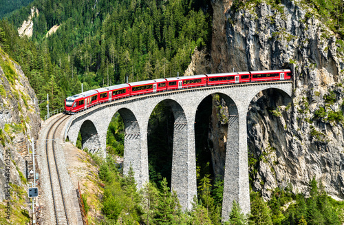 Passenger train crossing the Landwasser Viaduct in the Swiss Alps photo