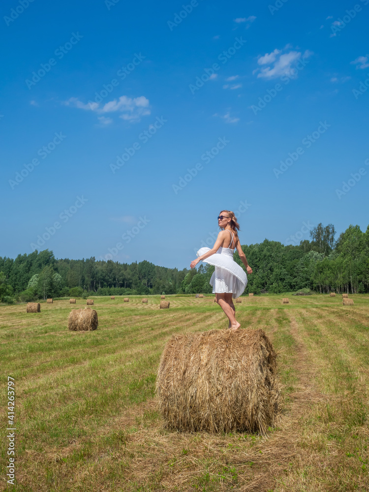 Girl dancing on a bale of hay on a summer day Girl dancing on a bale of hay on a summer day