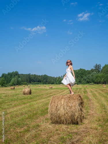 Girl dancing on a bale of hay on a summer day