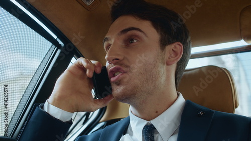 Happy male professional receiving positive news by mobile phone in automobile.