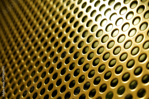 yellow metal lattice with holes as an abstract background photo