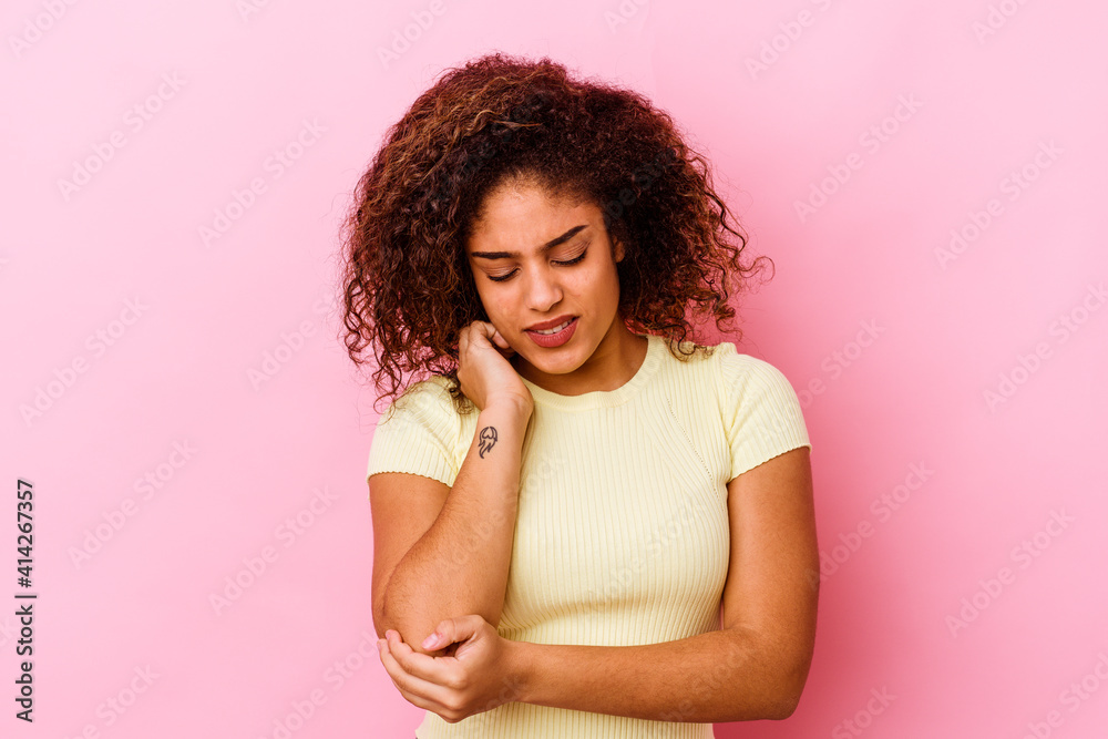 Young african american woman isolated on pink background massaging elbow, suffering after a bad movement. Young african american woman isolated on pink background massaging elbow, suffering after a bad movement.