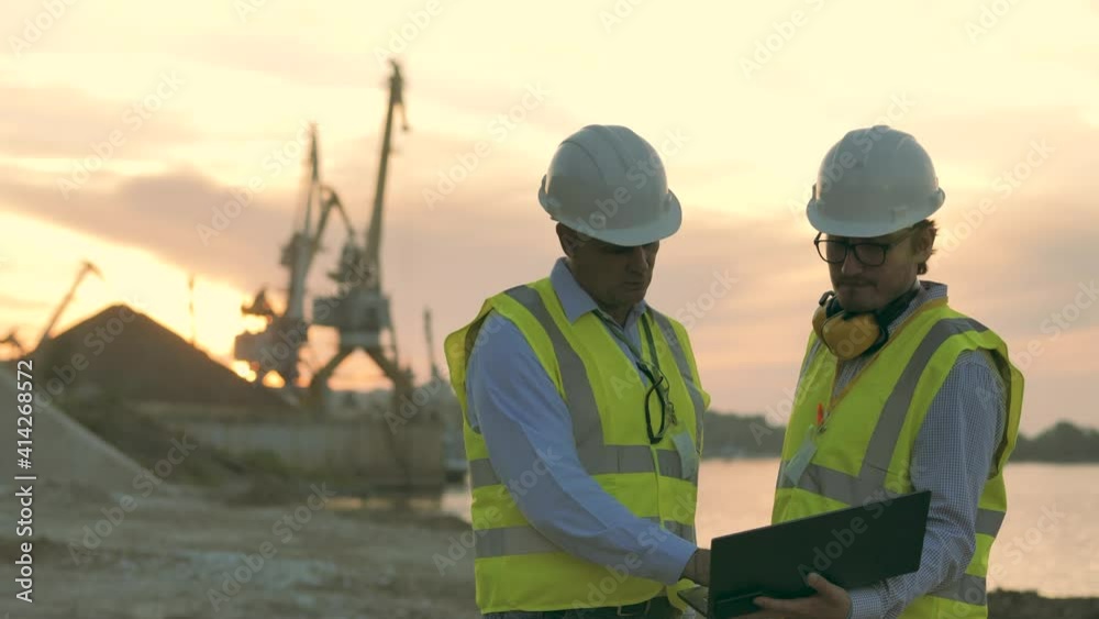 Industrial port with two engineers discussing plans