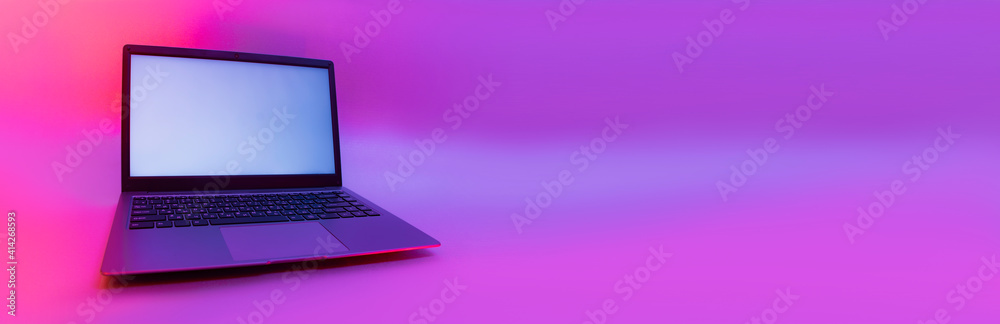 Slim modern laptop with white screen on the background creative light. Mockup in colorful bright neon UV blue and purple lights. Slim modern laptop with white screen on the background creative light. Mockup in colorful bright neon UV blue and purple lights.